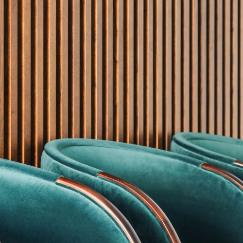 a row of chairs in front of a slat wall